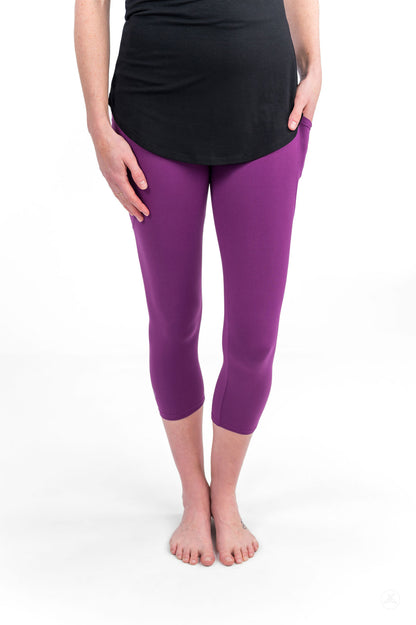 Woman wearing sweetlegs Deep Plum Pocket Crops standing barefoot with hands in pockets and black top on white background