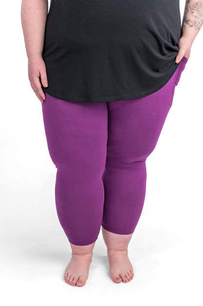 Plus size woman barefoot wearing sweetlegs Deep Plum Pocket Crops with black top and hands in pockets on white background