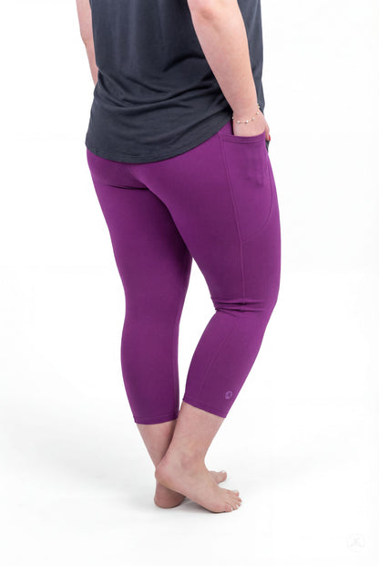 Person facing away wearing Deep Plum Pocket Crops by sweetlegs with hands in pockets standing barefoot on white background