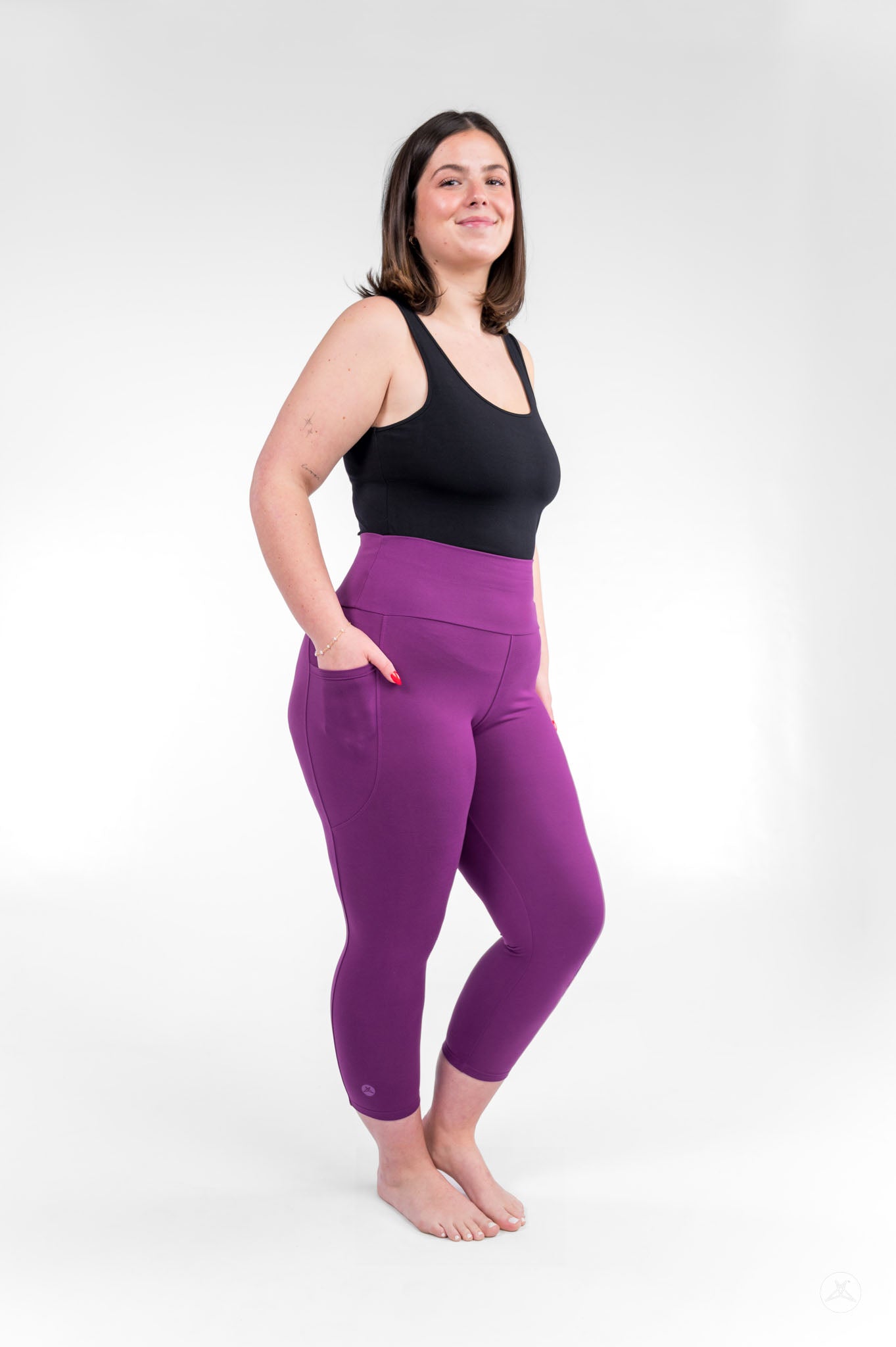 Plus size woman standing barefoot wearing sweetlegs Deep Plum High-Waisted Pocket Crops with black tank top and hands in pockets