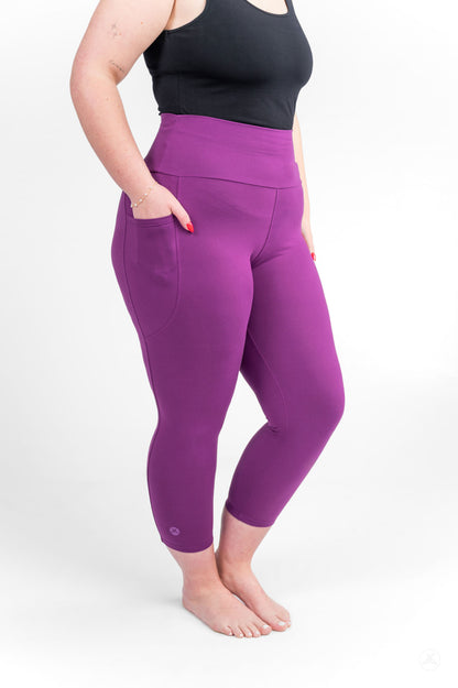 Person standing barefoot with hands in pockets wearing Deep Plum High-Waisted Pocket Crops by sweetlegs on white background