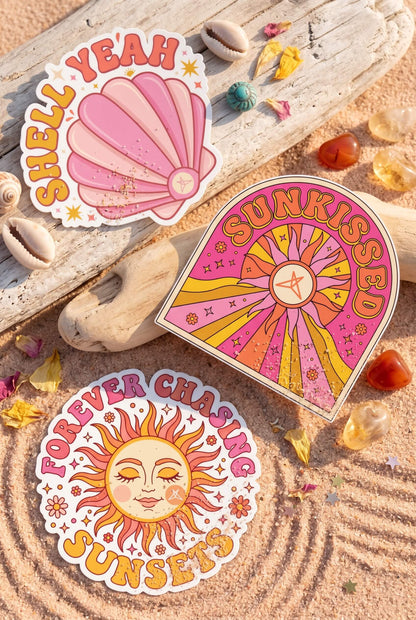 Three colorful sun and shell-themed stickers in warm tones from the Sun Chaser Sticker Pack by SweetLegs
