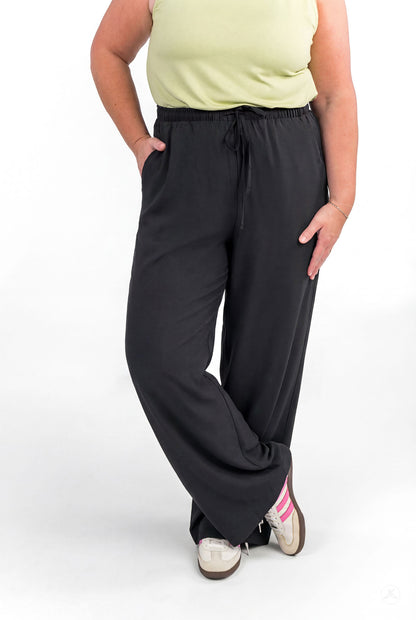 Plus size person with hands in pockets wearing black Breeze Wide-Leg Pant by sweetlegs standing relaxed on white background