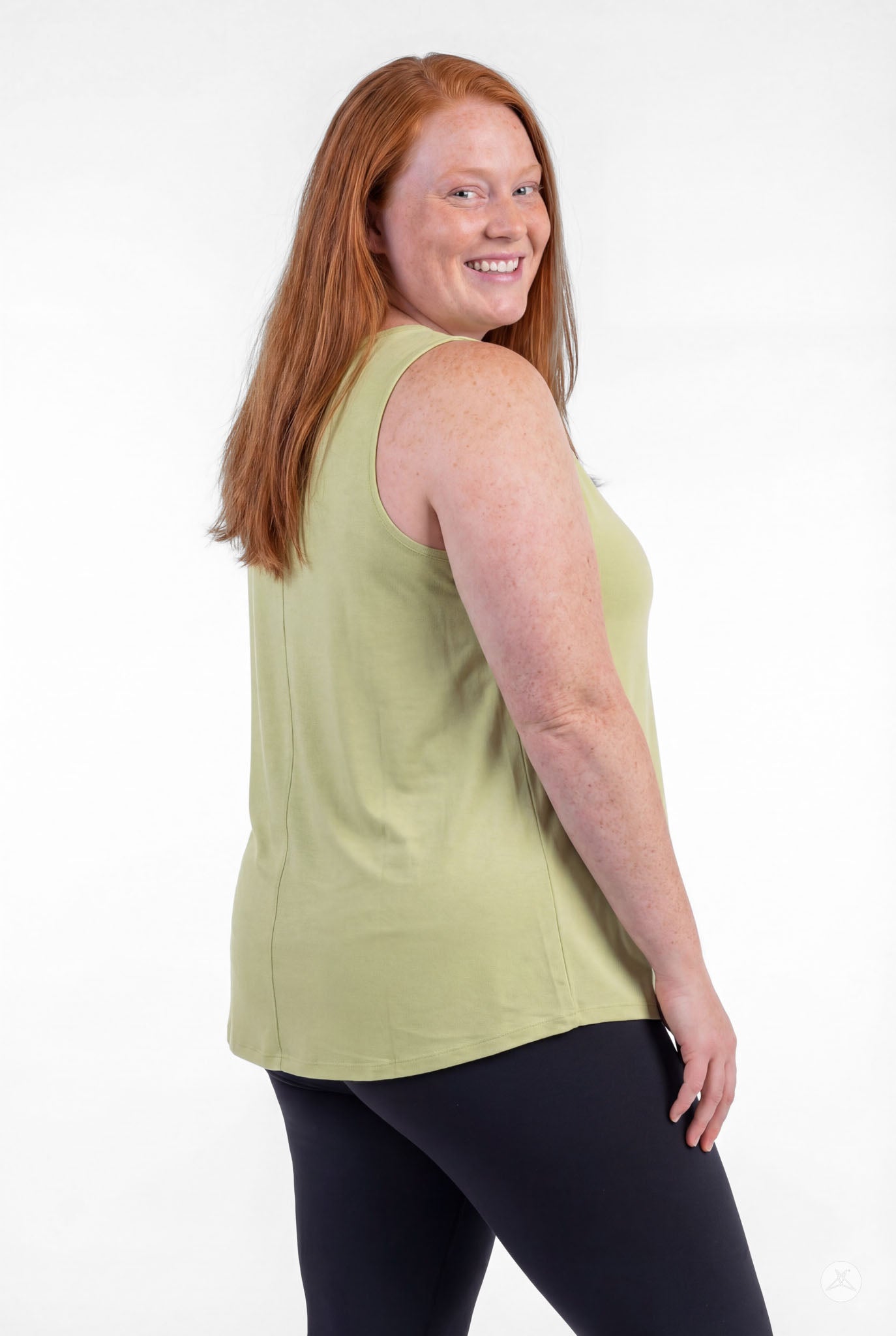 Plus size woman smiling wearing sweettops High Neck Tank in light green with black pants, posing confidently turned slightly back