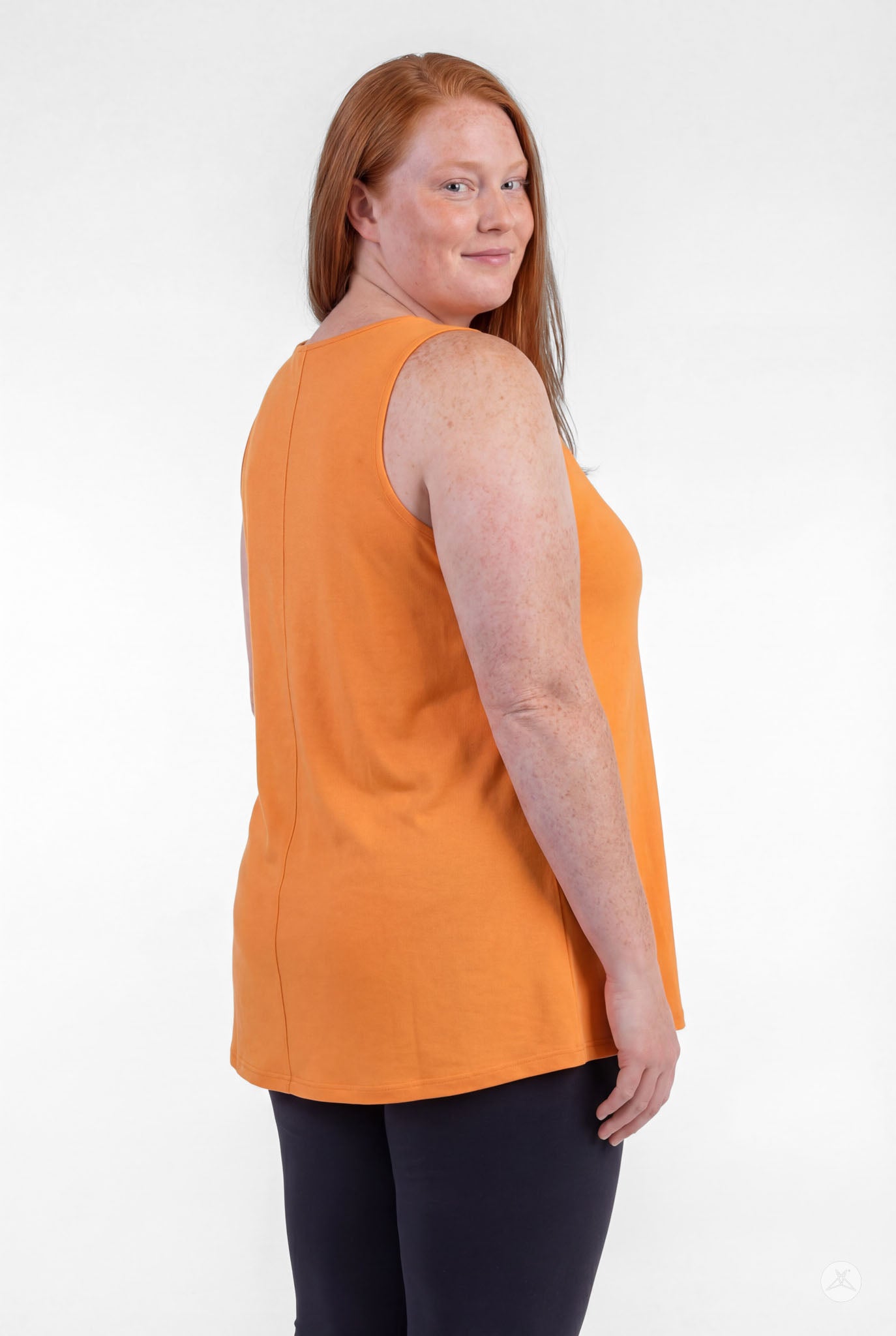 Plus size model wearing orange sleeveless High Neck Tank by sweettops smiling and looking over shoulder