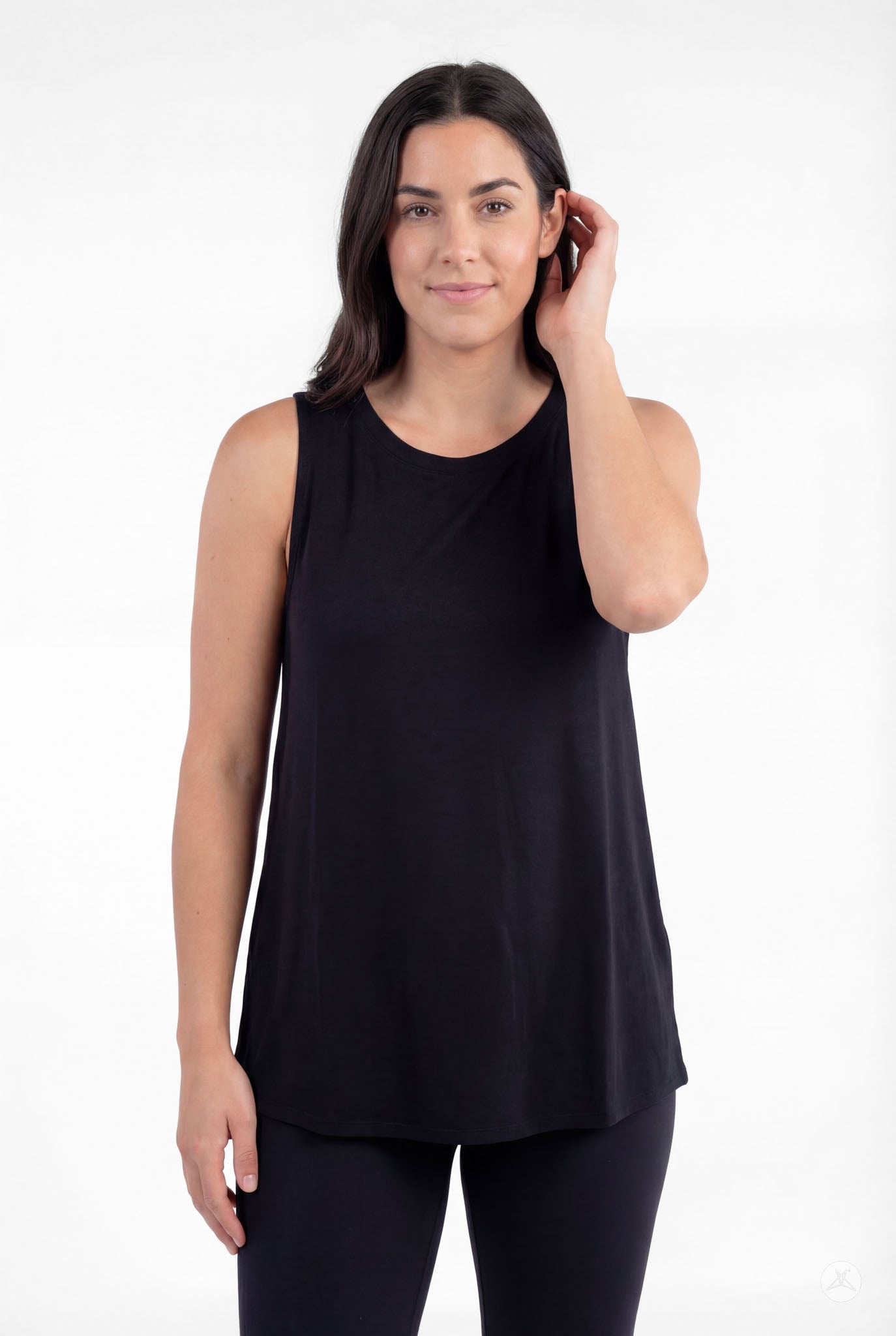 Woman wearing black sleeveless High Neck Tank by sweettops touching hair and smiling softly against plain background