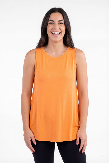 Smiling woman wearing orange High Neck Tank by sweettops standing relaxed with hands by sides against white background