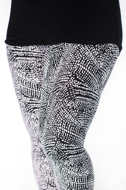 Close-up of SweetLegs Charmed leggings in black and white deconstructed snakeskin pattern on model legs